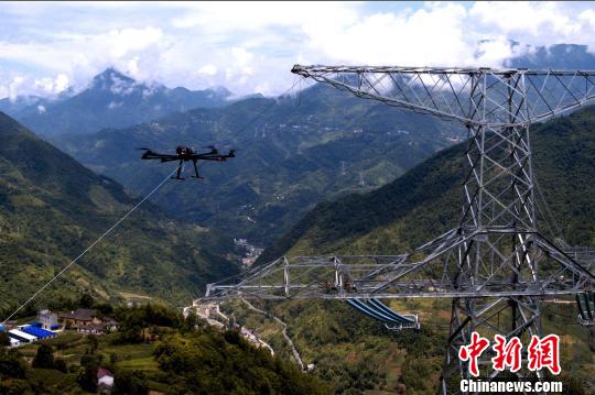 圖為重慶巫溪雞心嶺的±800千伏千伏酒泉-湖南特高壓工程渝1標段施工現場,國家電網重慶送變電公司作業人員正在用無人機牽引第一級引繩,進行放線施工作業。 國網重慶電力公司供圖 攝